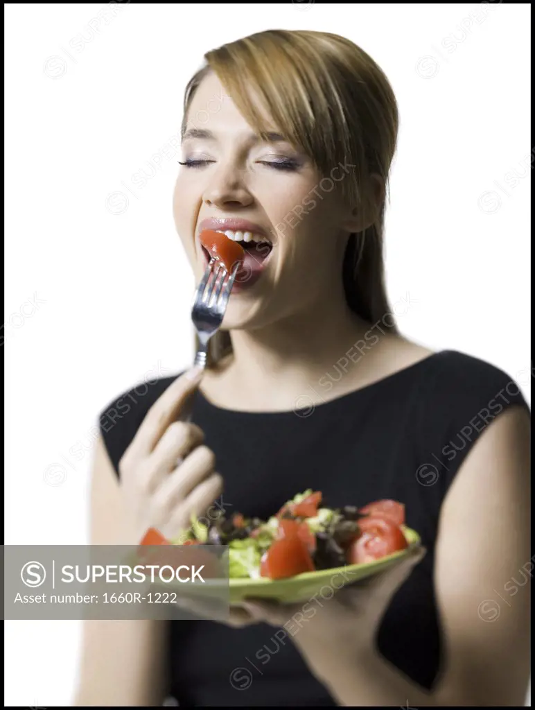 Close-up of a young woman eating a slice of tomato
