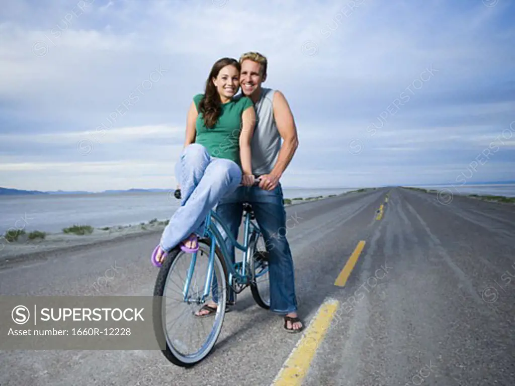 Portrait of a young woman and a mid adult man sitting on a bicycle