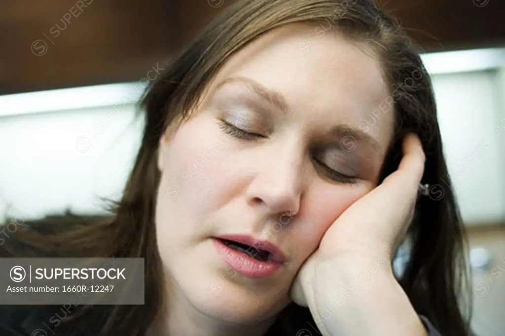 Close-up of a mid adult woman sleeping with her head in her hands
