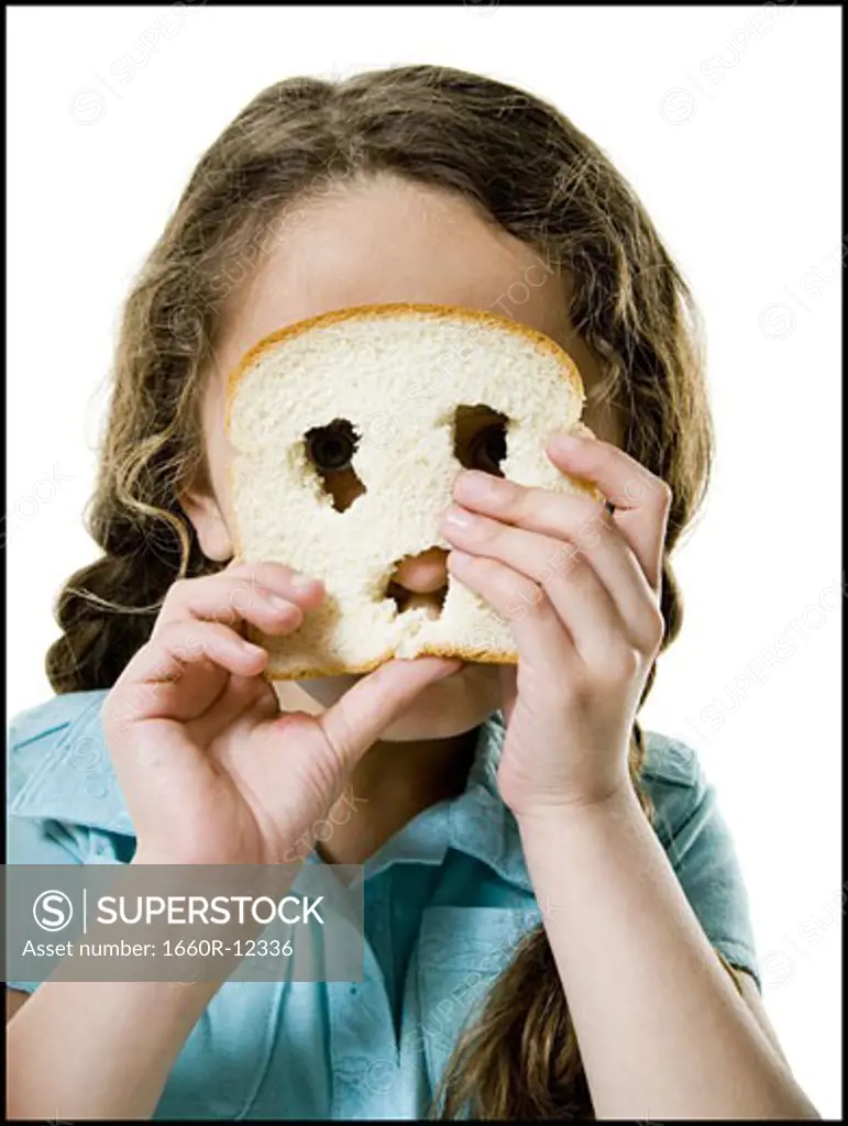 Portrait of a girl looking through a slice of bread