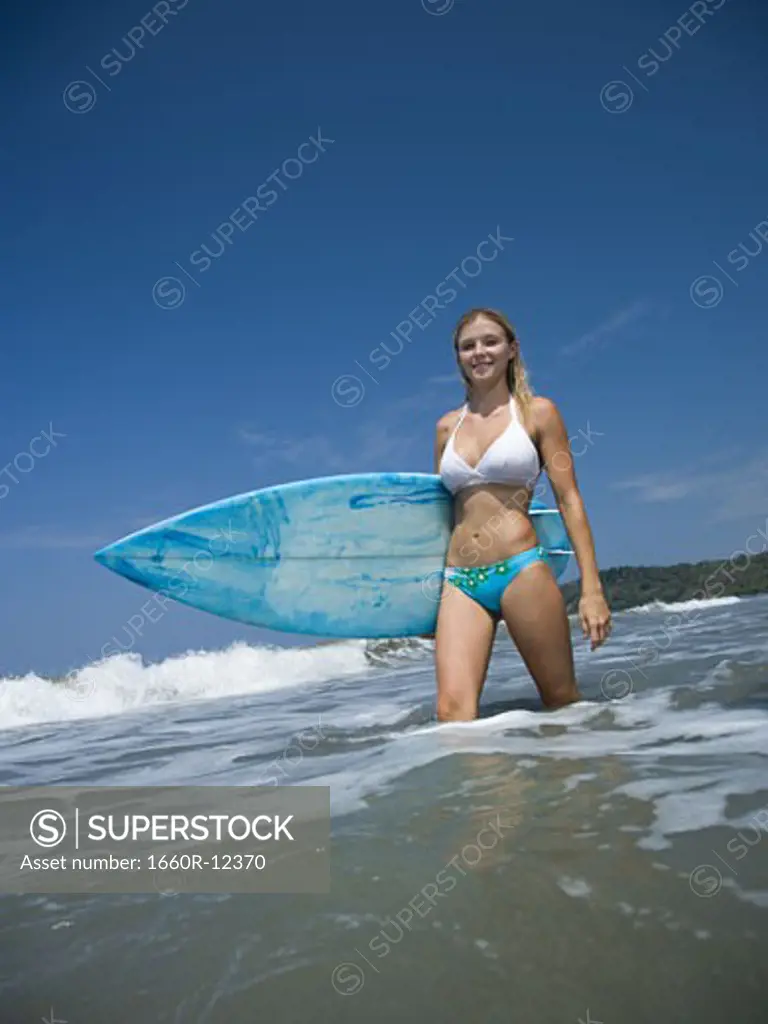 Portrait of a young woman holding a surfboard