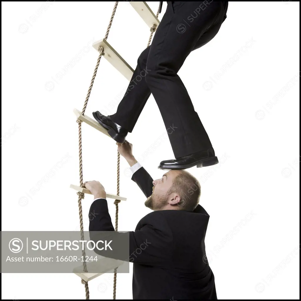 Profile of two businessmen climbing a ladder