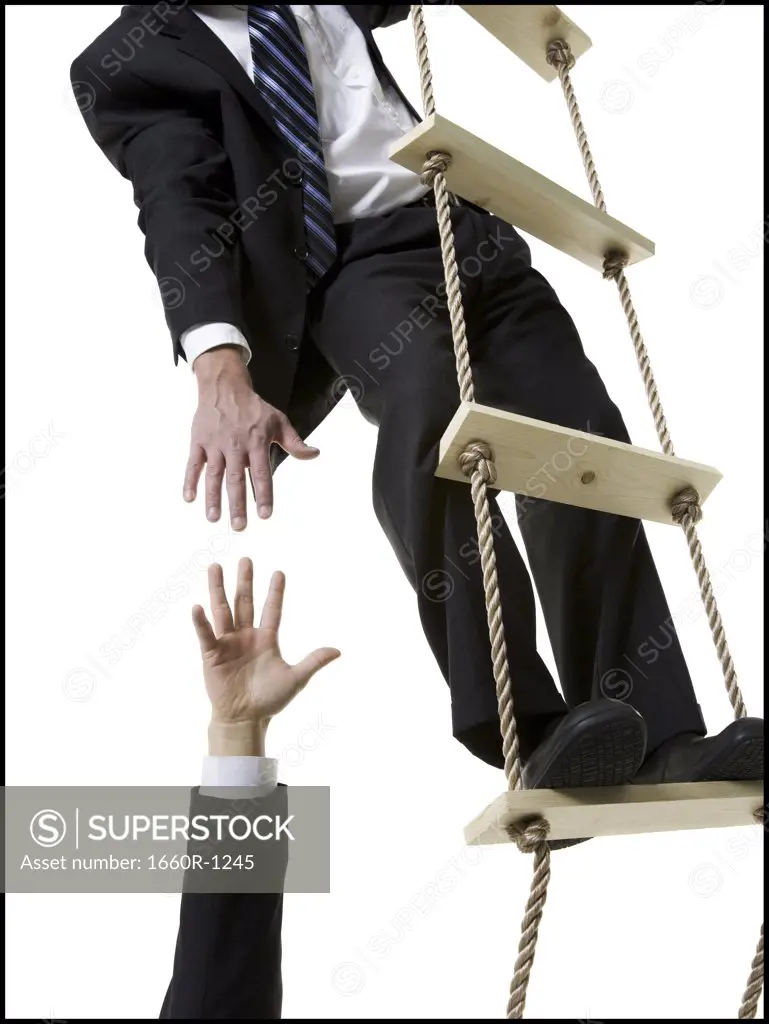 Low section view of a businessman reaching out for the hand of another businessman