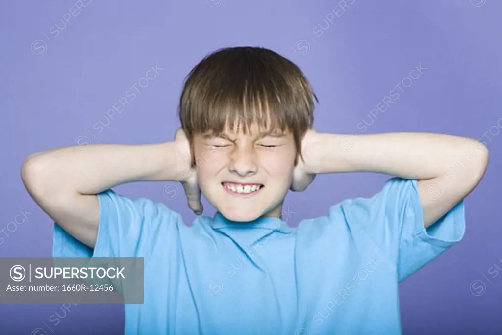 Close-up of a boy covering his ears