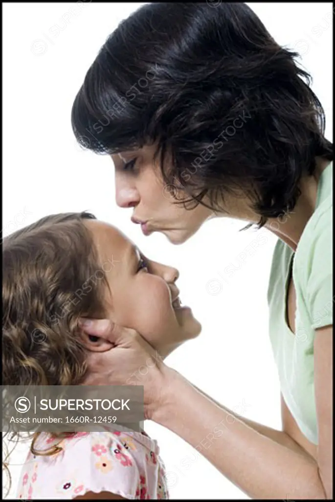 Close-up of a mid adult woman kissing her daughter's forehead