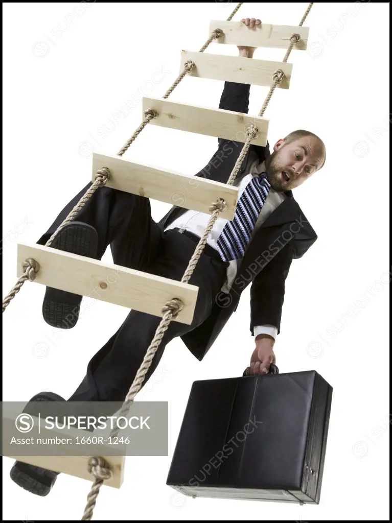 Low angle view of a businessman climbing a ladder holding a briefcase