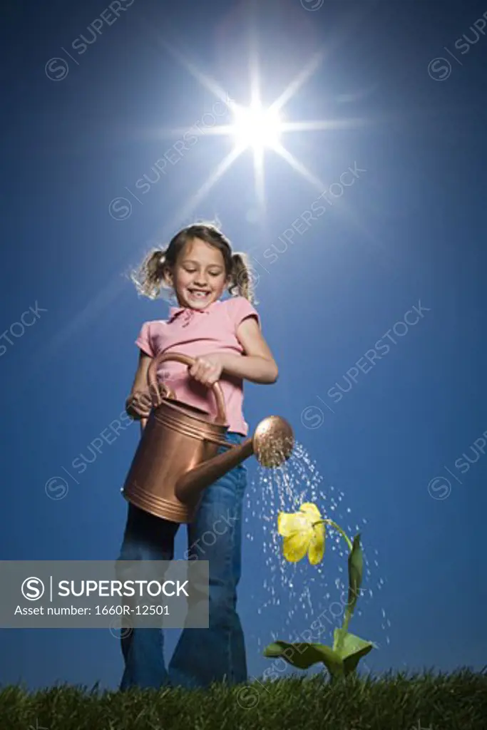 Low angle view of a girl watering a plant