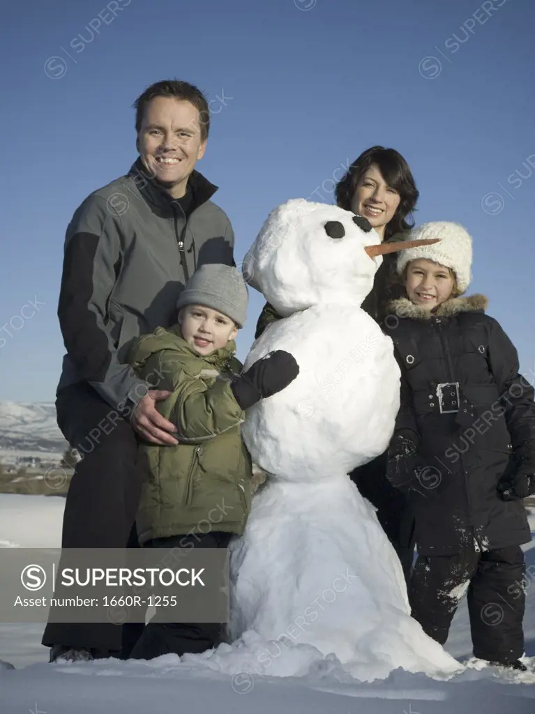 Portrait of a family standing next to a snowman