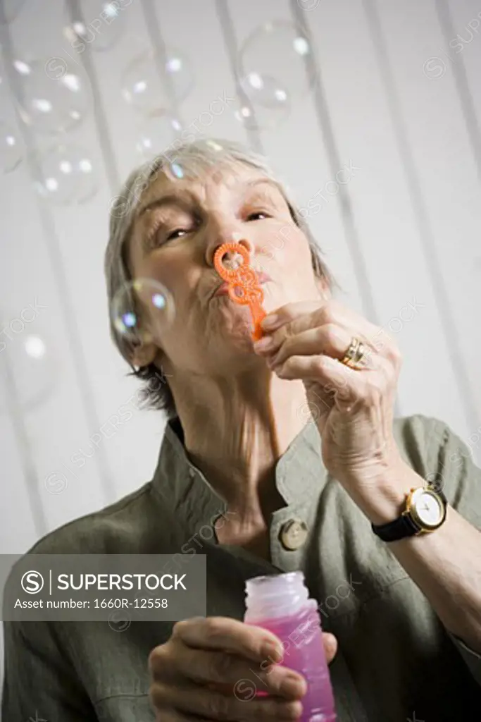 Portrait of an elderly woman blowing bubbles with a bubble wand