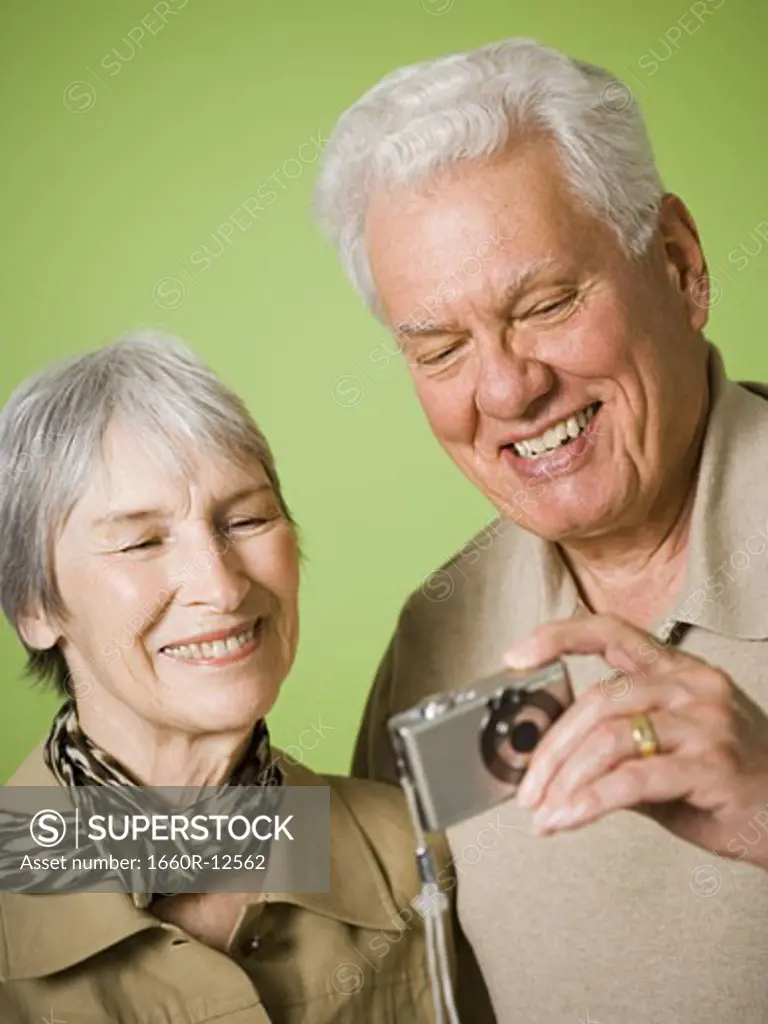 Close-up of an elderly couple looking at a digital camera