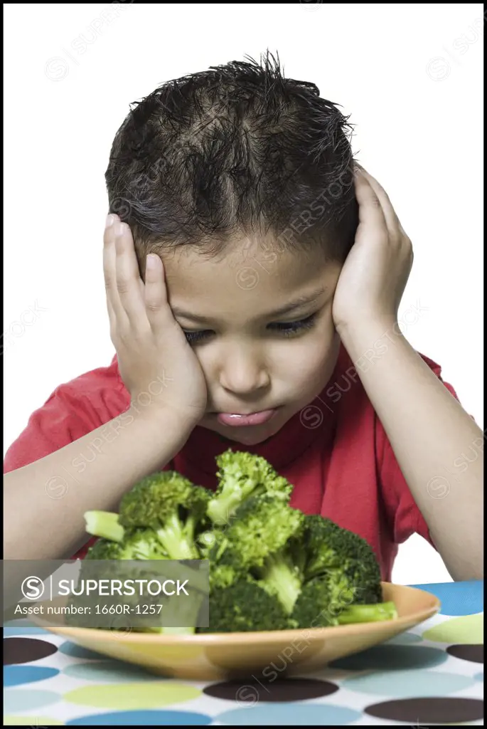 Close-up of a boy looking at broccoli in a plate