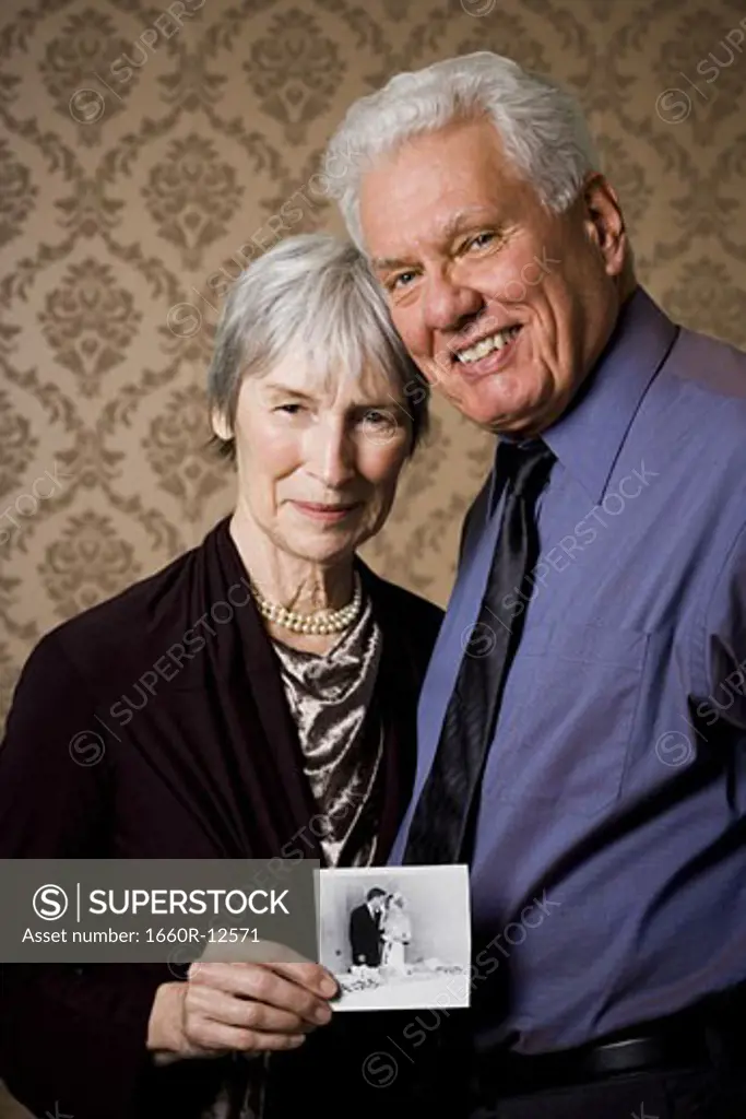 Portrait of an elderly couple showing a photograph