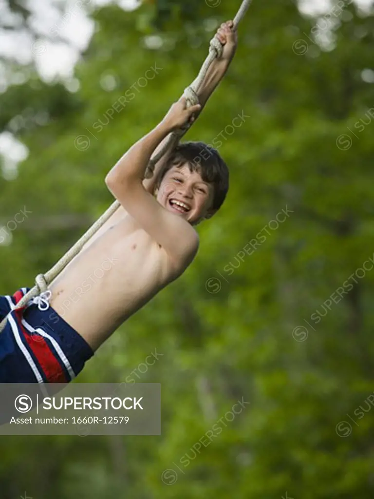 Portrait of a boy swinging on a rope