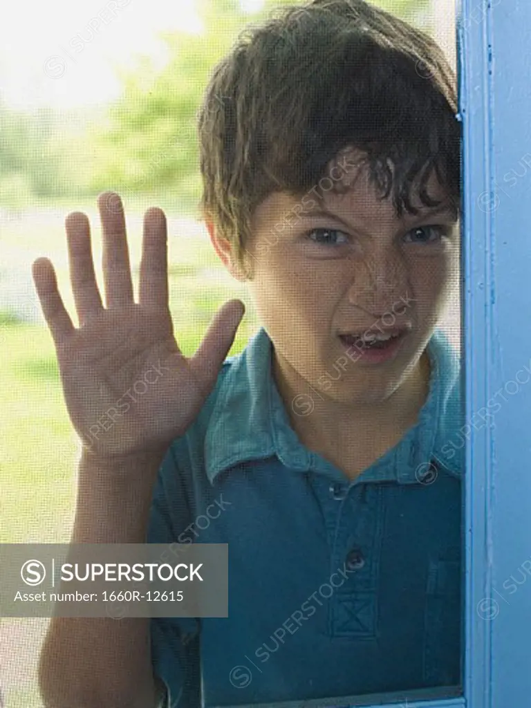 Portrait of a boy peeping through a window