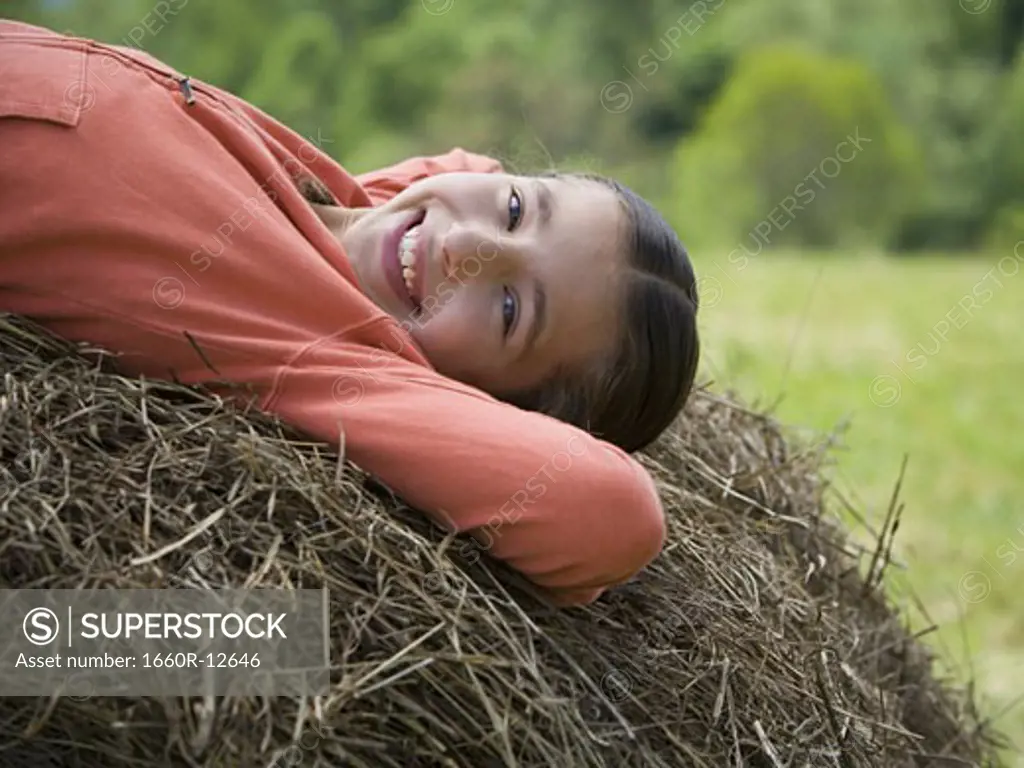 Portrait of a girl lying on a hay bale