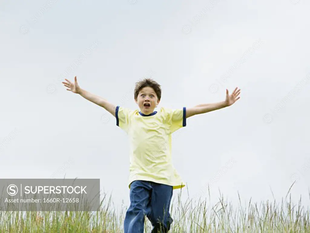 Portrait of a boy running with his arms outstretched