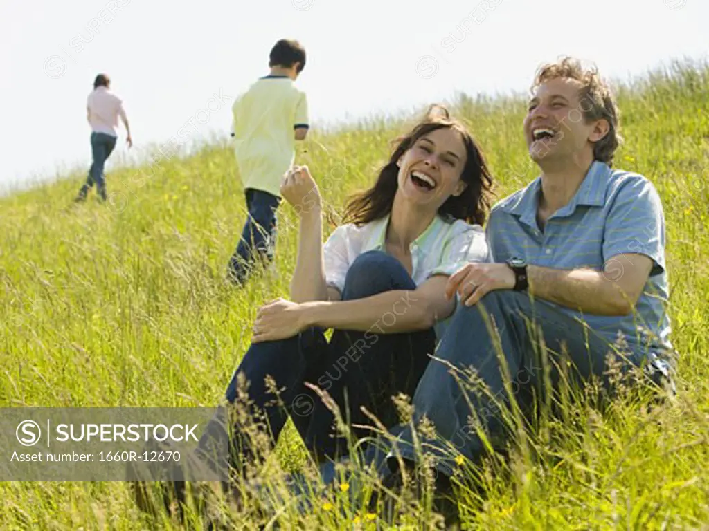 Close-up of a woman and a man sitting together and laughing in a field