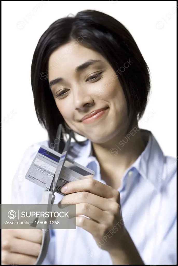 Close-up of a young woman cutting a credit card with a pair of scissors