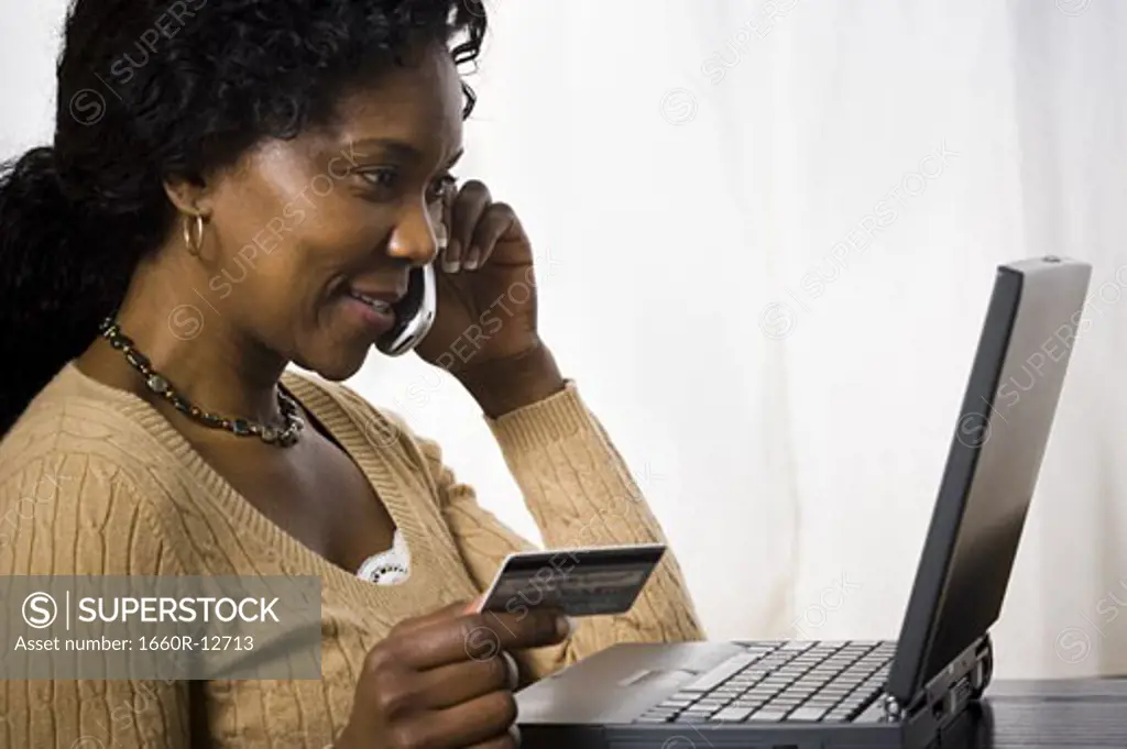 Profile of a mature woman talking on a mobile phone and holding a credit card