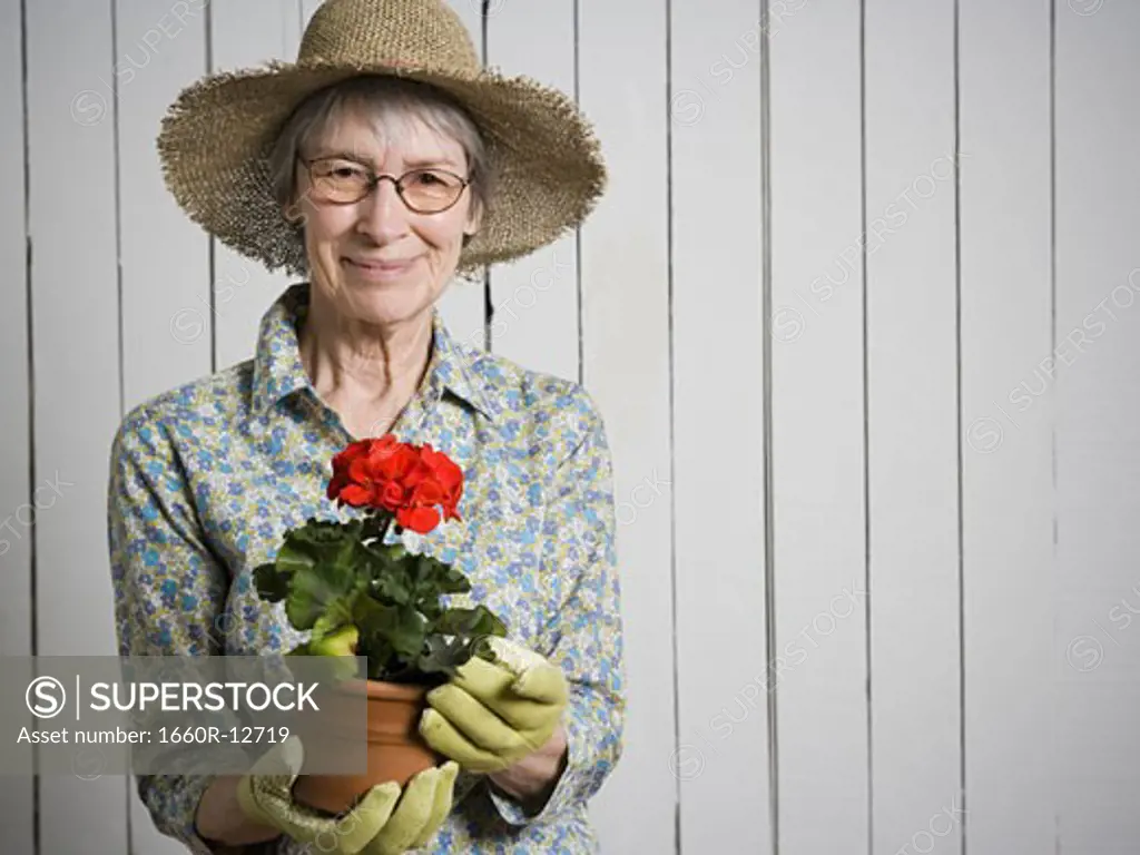 Portrait of an elderly woman holding a potted flower plant