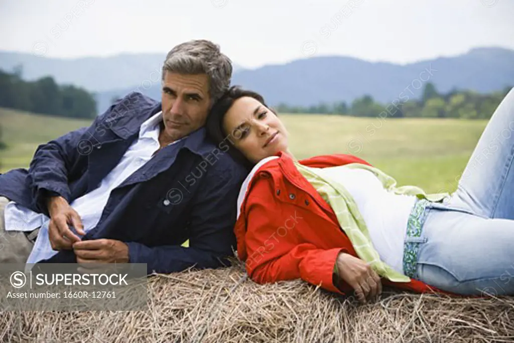 Portrait of a woman and a man resting on a hay bale