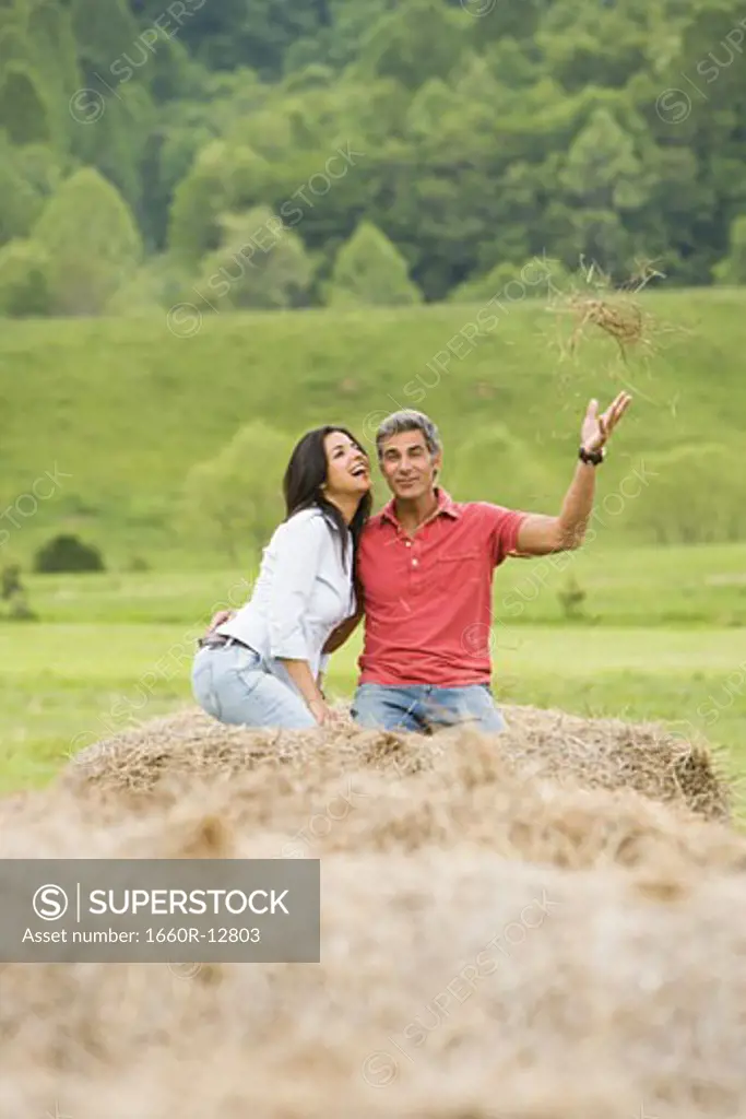 man and a woman sitting on a hay bale