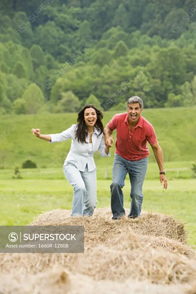 Portrait of a man and a woman running on hay bales