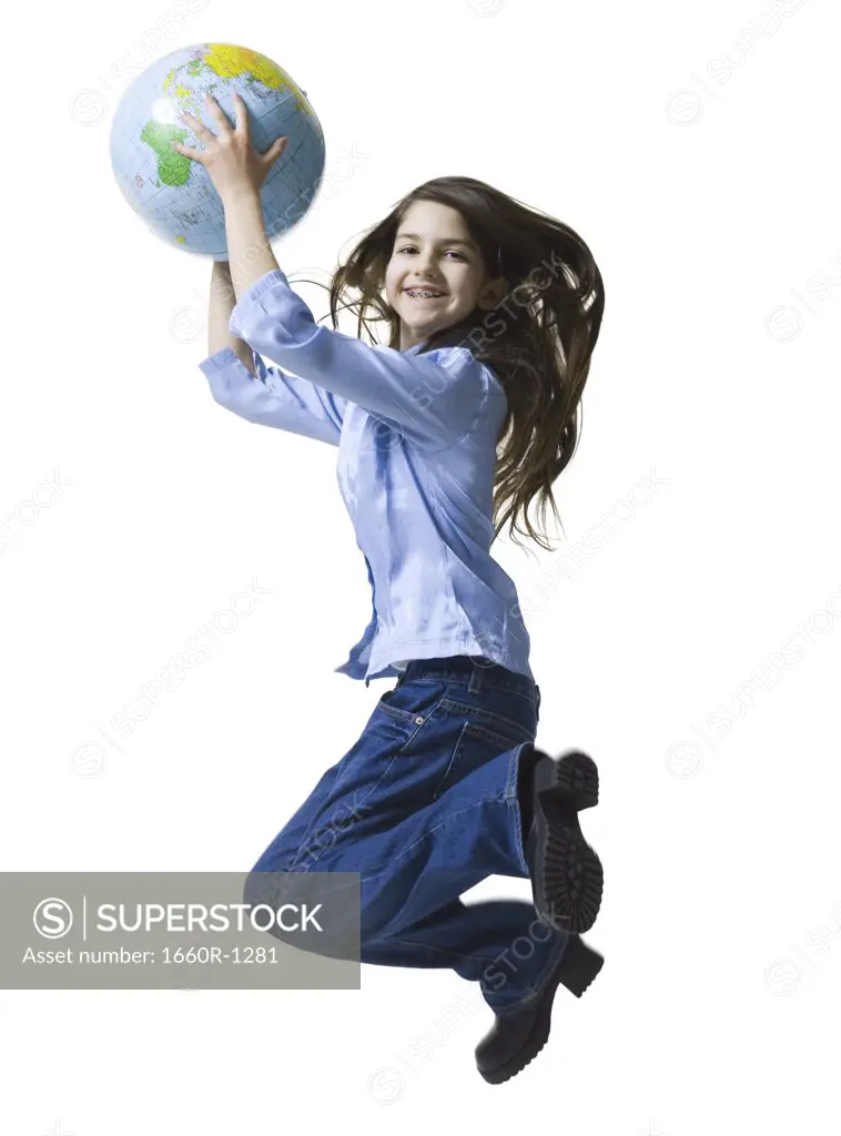 Portrait of a teenage girl jumping holding a globe