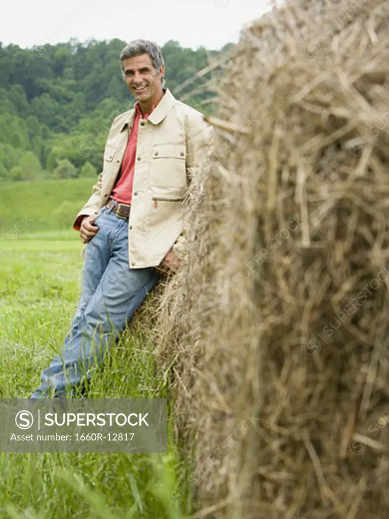Portrait of a man leaning against a hay bale
