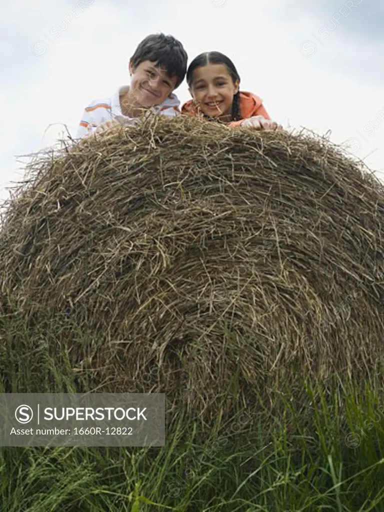 Portrait of a boy and a girl lying on top of a haystack