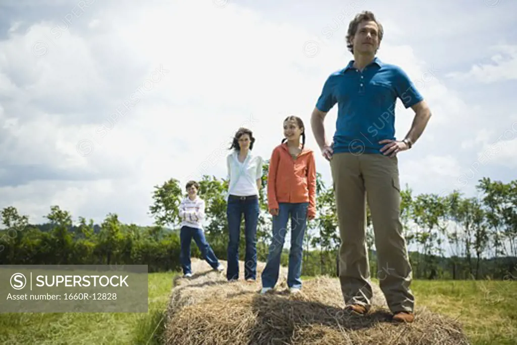 man and a woman standing with their children on hay bales