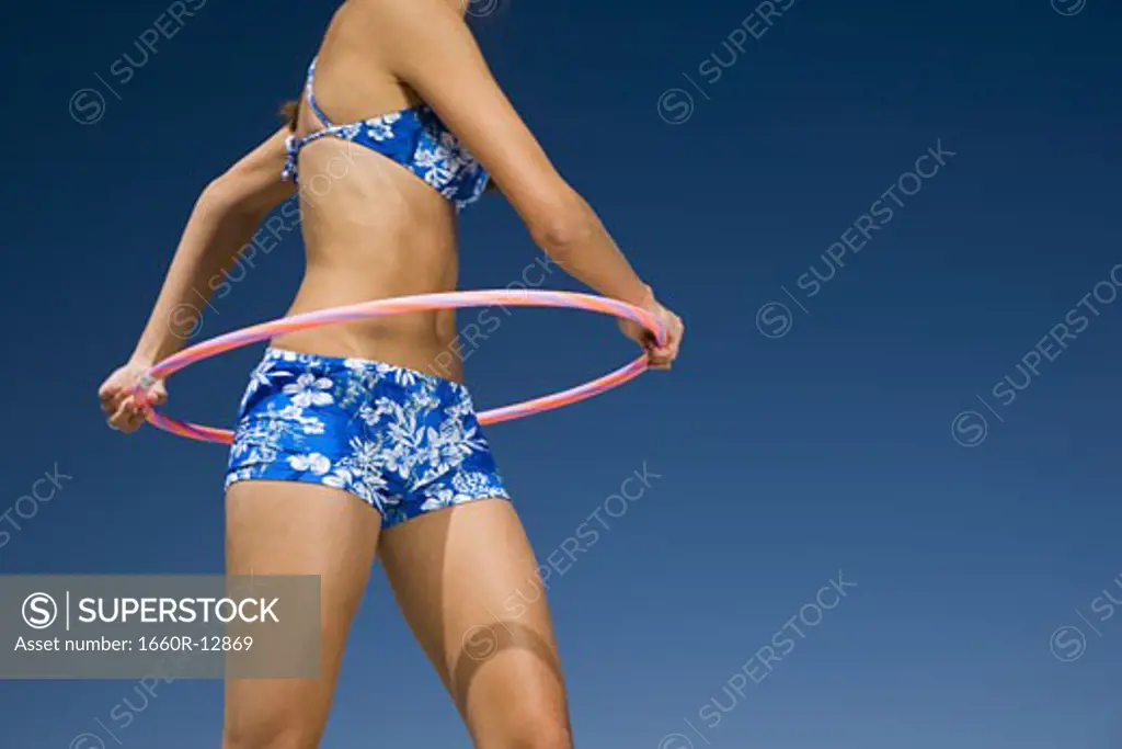 Mid section view of a young woman playing with a hula hoop