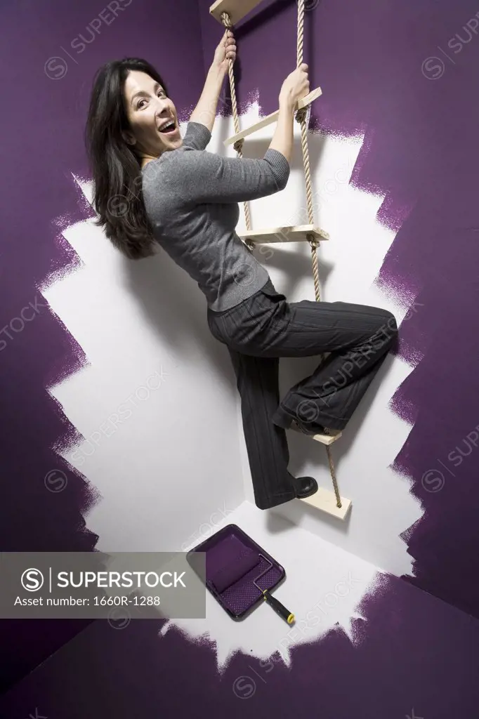 Portrait of a mid adult woman climbing a ladder