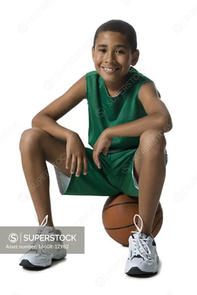 Portrait of a boy sitting on a basketball