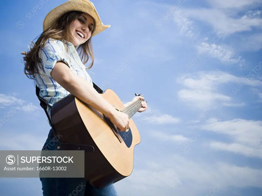 Low angle view of a young woman playing the guitar