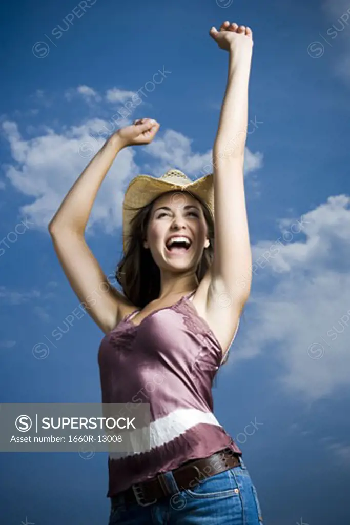 Low angle view of a young woman with her arms raised