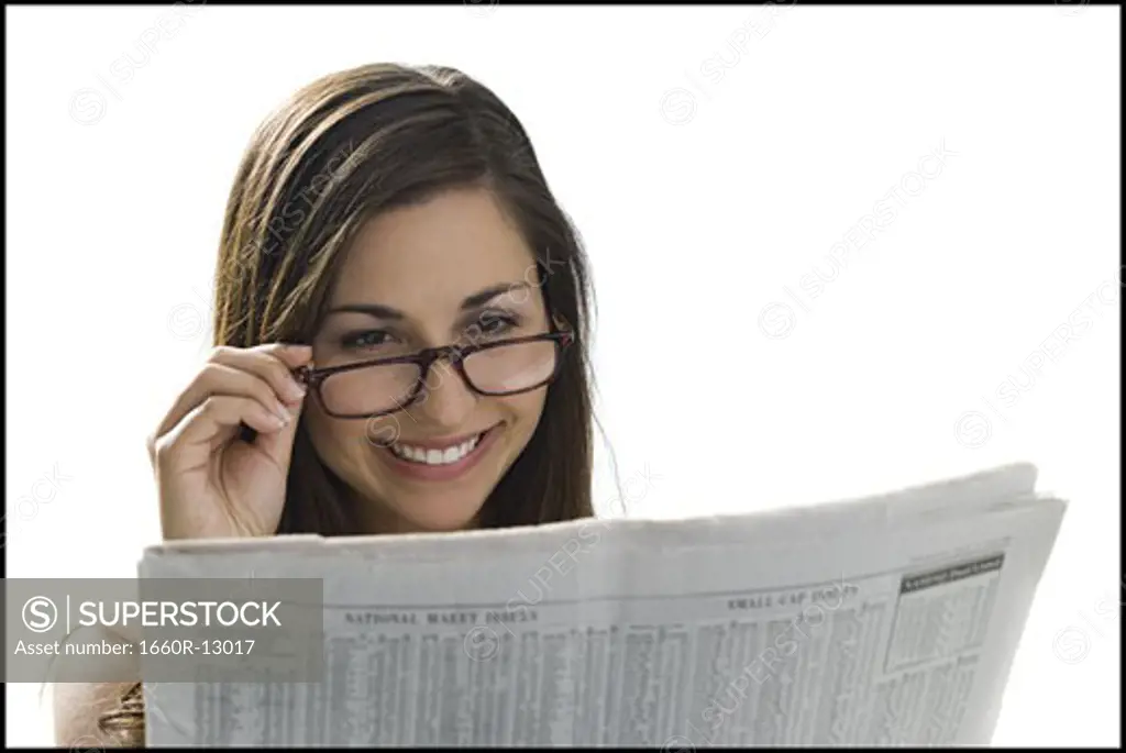 Close-up of a young woman reading a newspaper and smiling