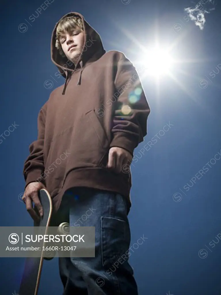 Low angle view of a teenage boy holding a skateboard