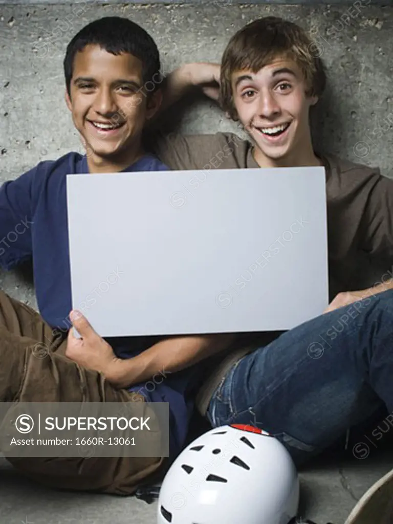 Portrait of two teenage boys holding a blank sign and smiling