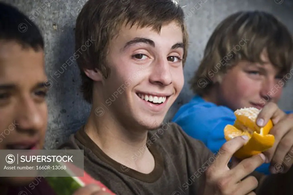 Three teenage boys eating fruit