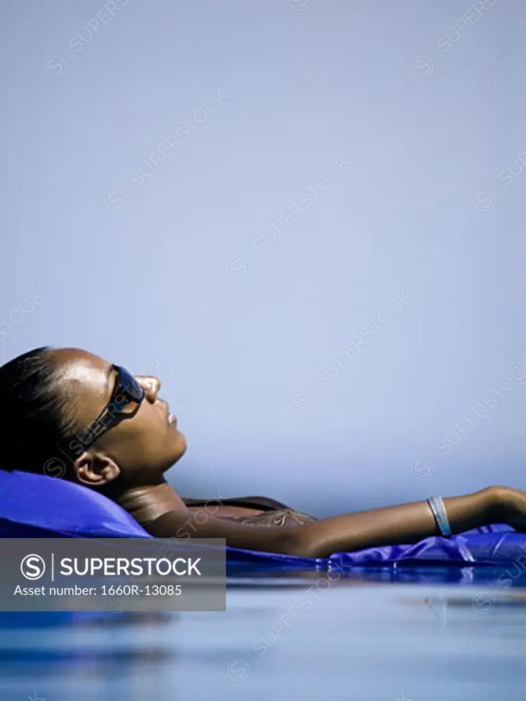 Profile of a young woman floating in water on an inflatable raft