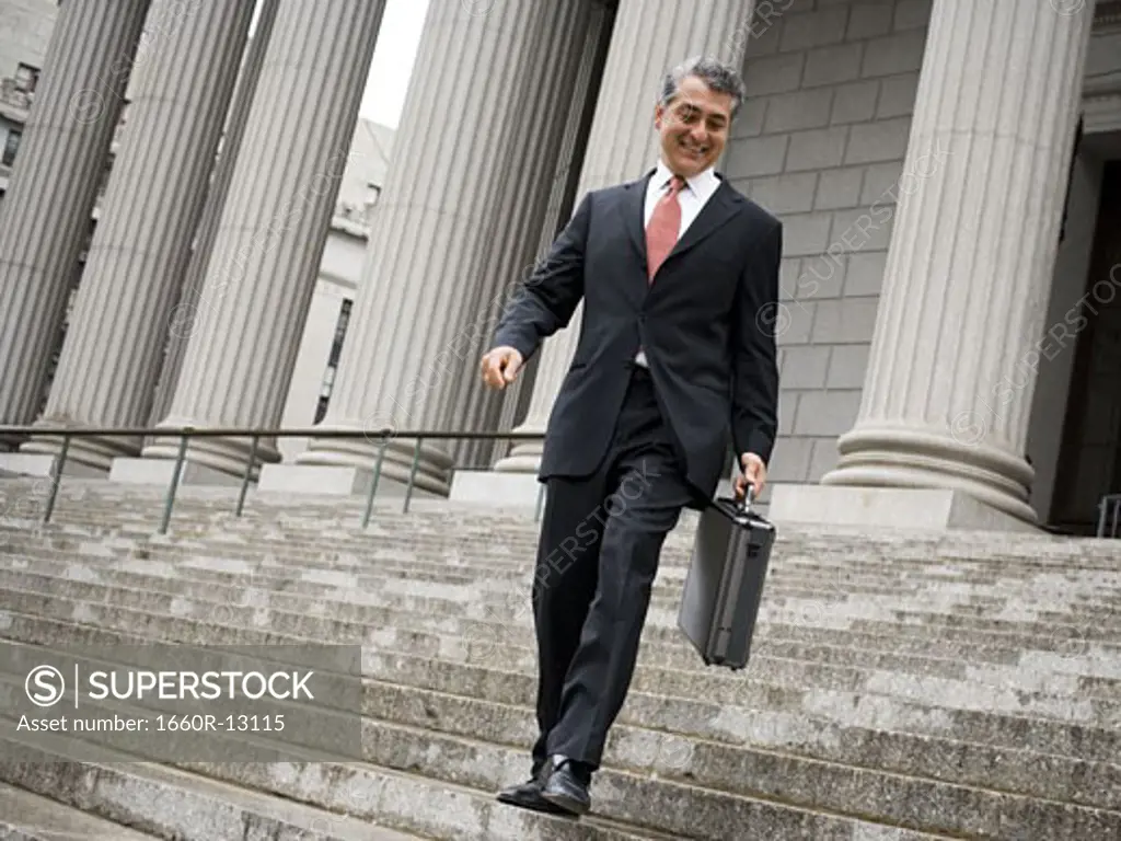 Low angle view of a male lawyer walking down the steps of a courthouse