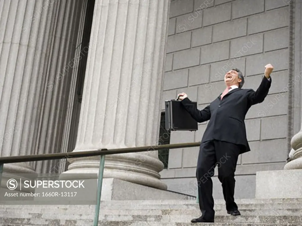 Low angle view of a male lawyer laughing and walking down the steps of a courthouse