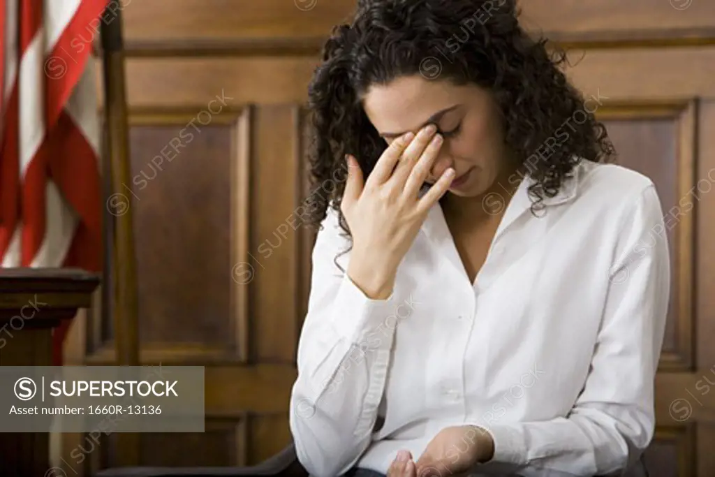 An upset female witness sitting in a courtroom