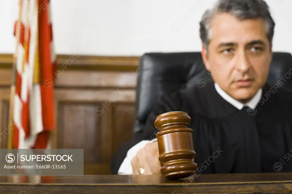 A male judge hitting a gavel on the bench