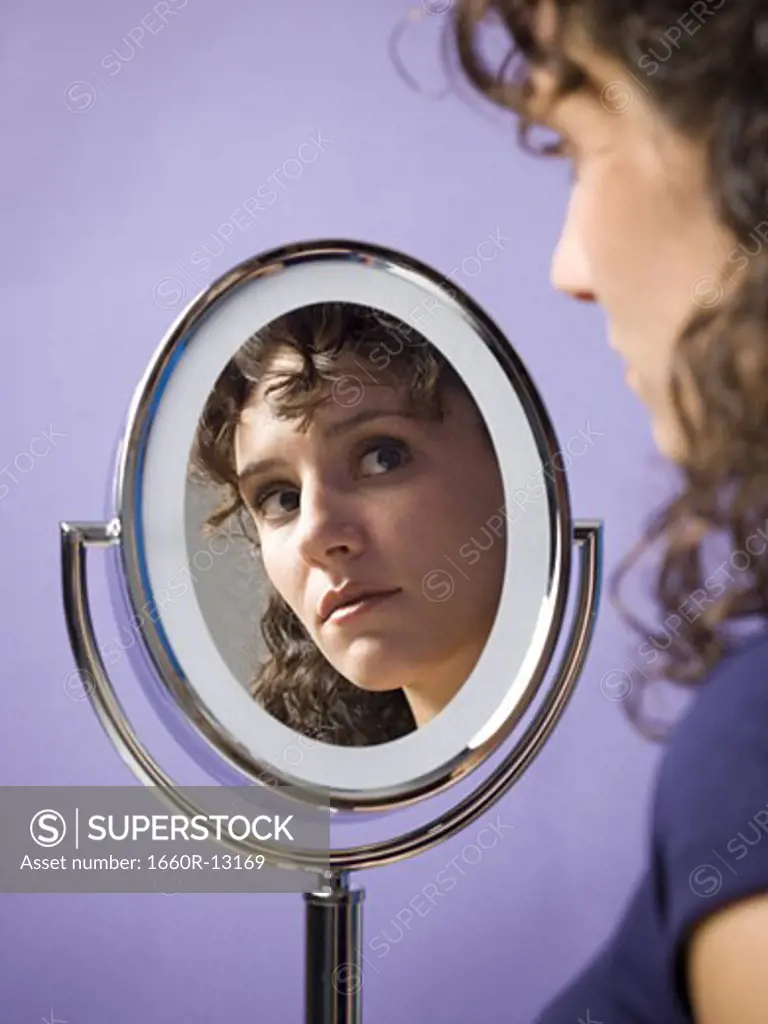 Close-up of a young woman looking into a mirror