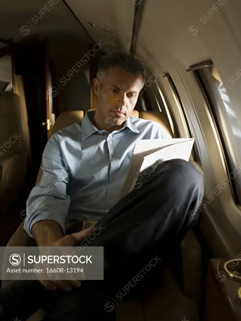 A businessman reading a newspaper in an airplane