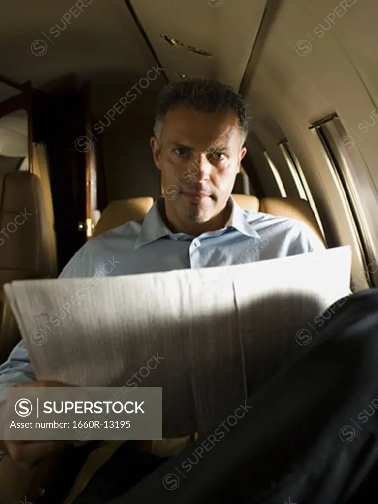 Portrait of a businessman holding a newspaper in an airplane