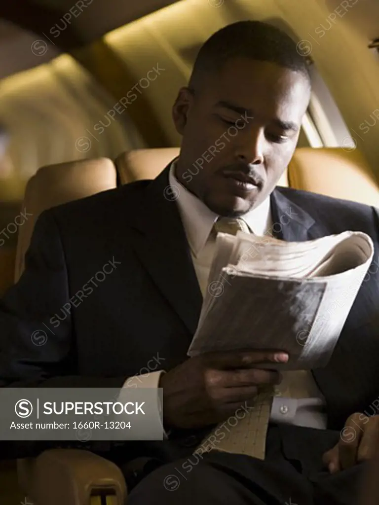 A businessman reading a newspaper in an airplane