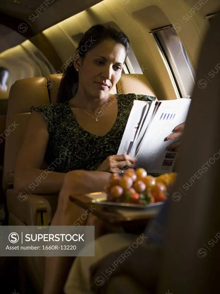 A businesswoman reading a magazine on an airplane